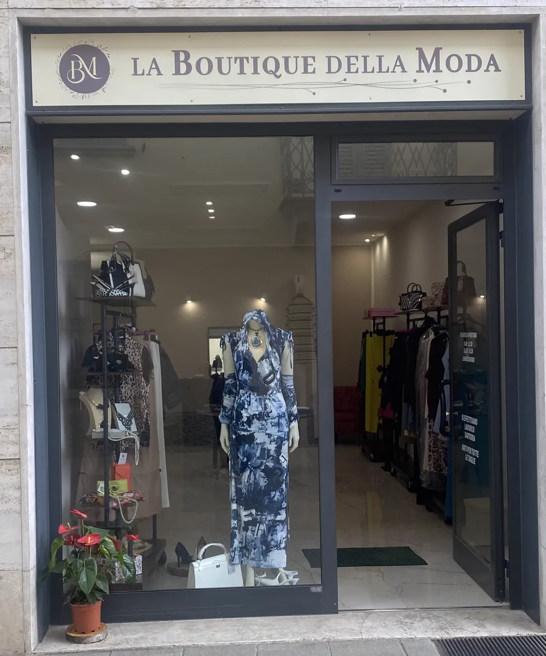 Ingresso e vetrina con insegna 'La Boutique della Moda' e manichino in abito blu fantasia